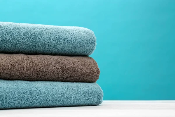 Pila di asciugamani puliti morbidi sul tavolo contro lo sfondo di colore. Spazio per testo — Foto Stock