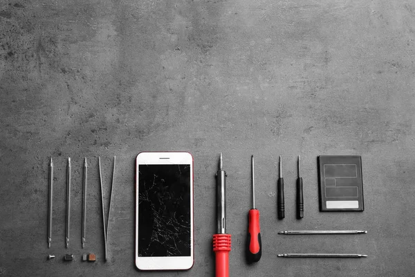 Broken mobile phone and repair tools on table, flat lay. Space for text