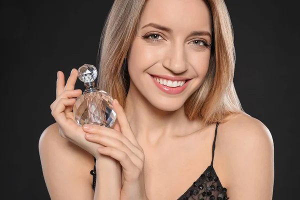 Jeune femme avec bouteille de parfum sur fond noir — Photo