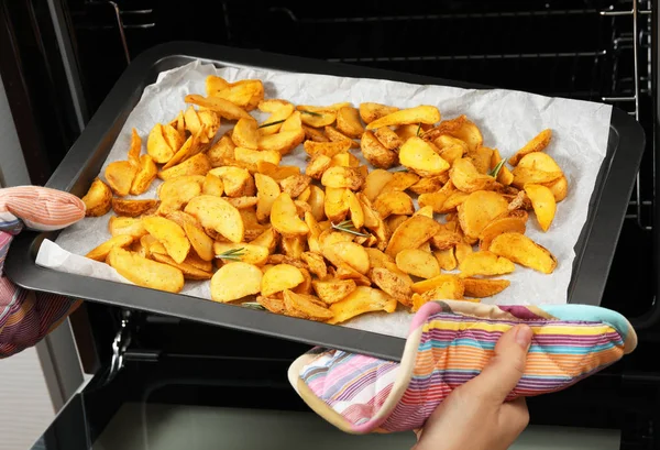 Mujer sacando patatas asadas calientes del horno, primer plano —  Fotos de Stock