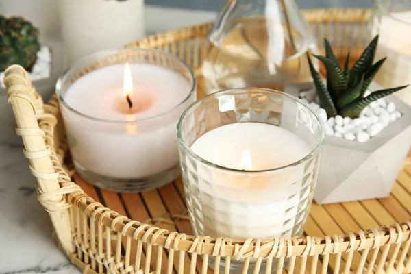 Bandeja de vime com velas em chamas e planta de sala na mesa — Fotografia de Stock