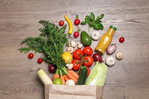 Paquete de papel con verduras frescas y frutas sobre fondo de madera, puesta plana —  Fotos de Stock