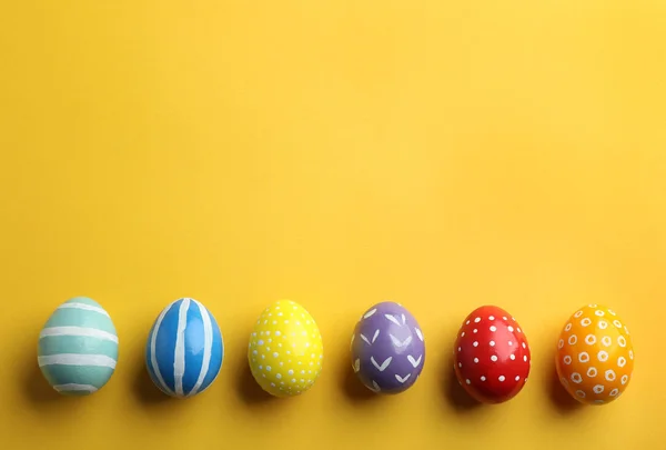 Composição de colocação plana de ovos de Páscoa pintados sobre fundo de cor, espaço para texto — Fotografia de Stock