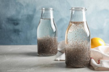 Renk arka plan karşı masada su ve chia tohumu şişeleri ile Kompozisyon. Metin için alan