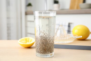 Composition with glass of water and chia seeds on table against blurred background clipart