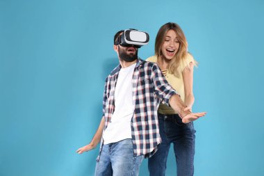 Genç adam VR kulaklık ve renk arka plan üzerinde duygusal kadın ile video oyunları oynuyor