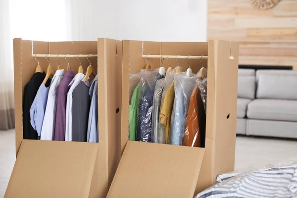 Boîtes d'armoire en carton avec vêtements sur cintres dans le salon — Photo