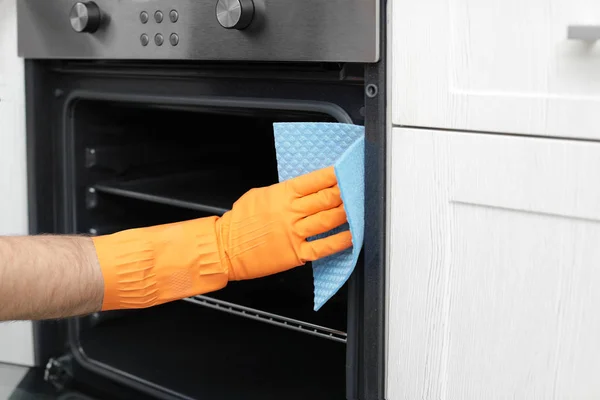 Jovem limpando forno com pano na cozinha, close-up — Fotografia de Stock