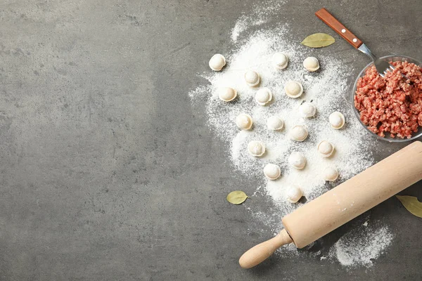 Cuenco con carne picada, rodillo y albóndigas crudas sobre fondo gris, puesta plana. Espacio para texto — Foto de Stock