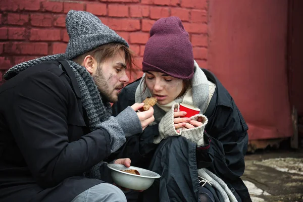 Pobre jovem casal com pão na rua suja — Fotografia de Stock