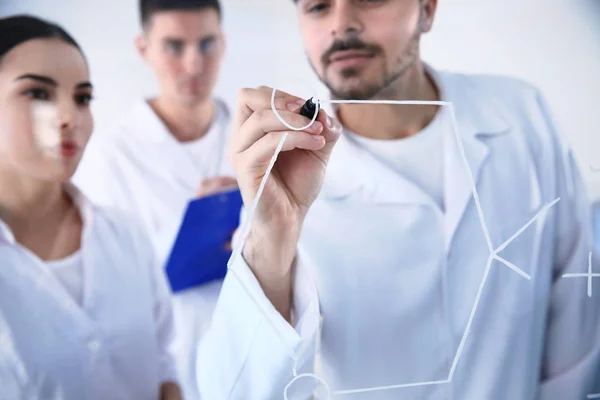 Estudiantes de medicina escribiendo fórmula química en pizarra de vidrio en laboratorio —  Fotos de Stock
