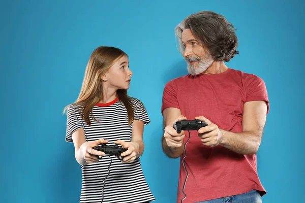 色の背景にコントローラでビデオゲームをプレイ成熟した男と十代の女の子 — ストック写真