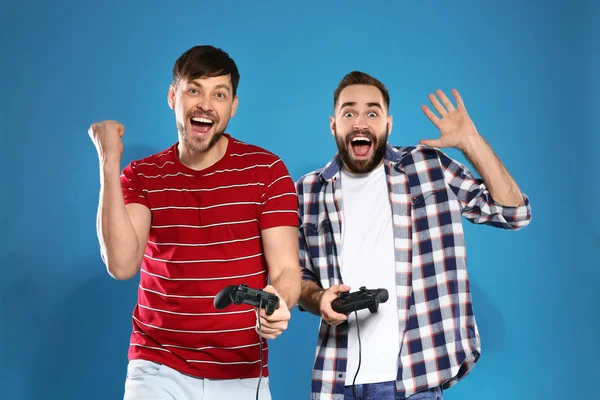 Duygusal erkekler renkli arka plan üzerinde denetleyicileri ile video oyunları oynuyor — Stok fotoğraf