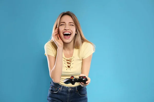 Mujer joven emocional jugando videojuegos con controlador en el fondo de color. Espacio para texto —  Fotos de Stock