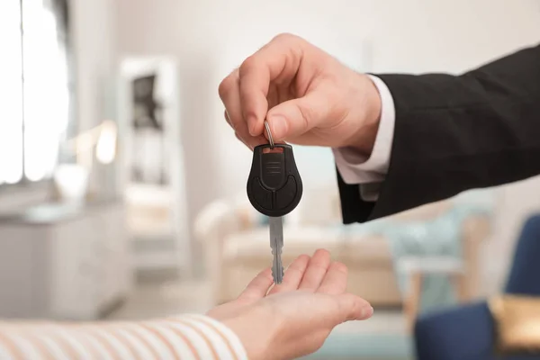 Um homem a dar a chave do carro a uma mulher dentro de casa, de perto. Espaço para texto — Fotografia de Stock