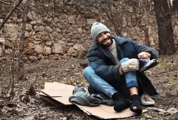 市立公園で段ボールに座っている貧しいホームレスの男 — ストック写真