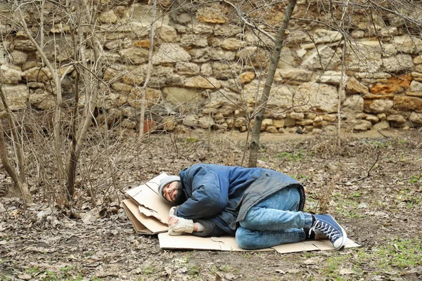 都会の公園で地面に横たわっている貧しいホームレスの男 — ストック写真