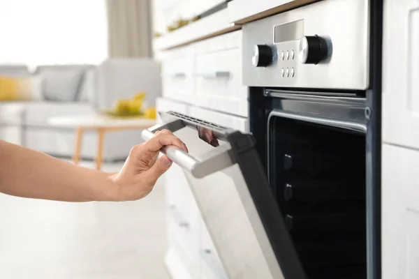 Donna che apre la porta del forno in cucina, primo piano — Foto Stock