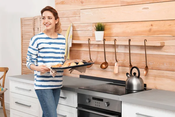 Young woman with sheet pan of oven baked cookies in kitchen