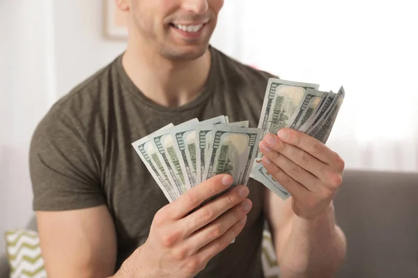 Young man counting money on blurred  background, closeup — Stock Photo, Image