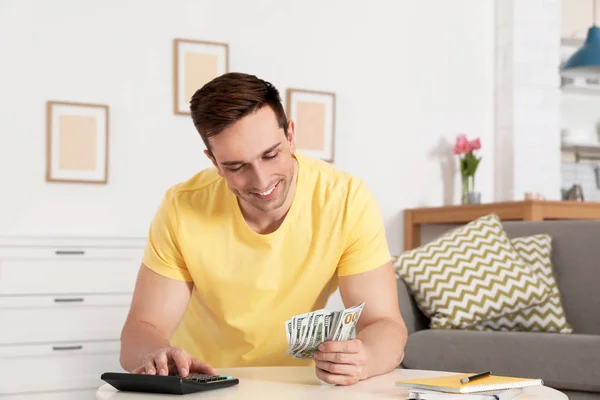 Szczęśliwy człowiek liczenia pieniędzy w tabeli w salonie — Zdjęcie stockowe