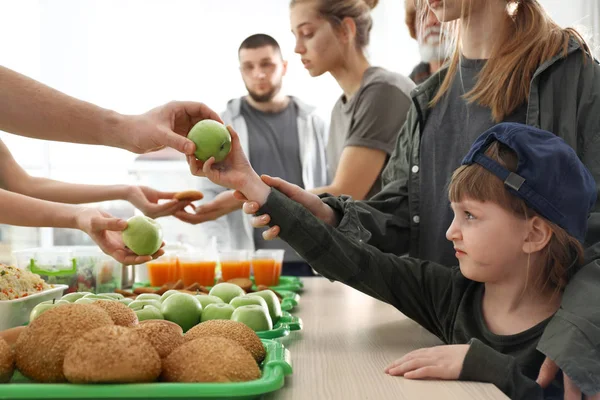 Voluntario dando manzana a la pobre chica en el interior — Foto de Stock