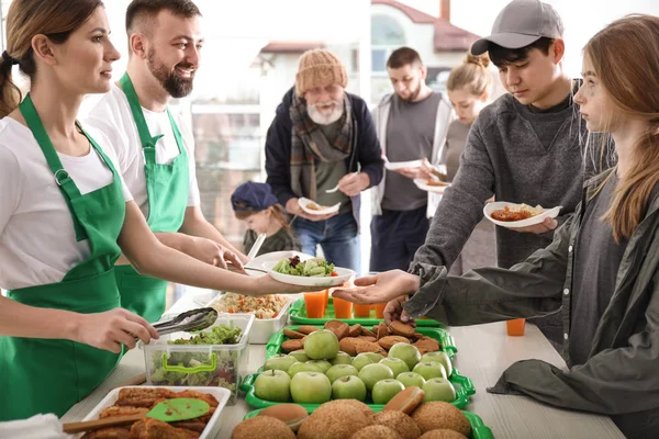 貧しい人々に屋内で食べ物を与えるボランティア — ストック写真