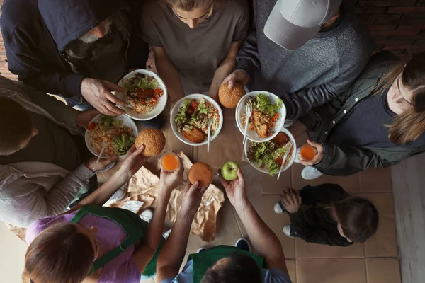 Бедные люди с тарелками еды в помещении, вид сверху — стоковое фото