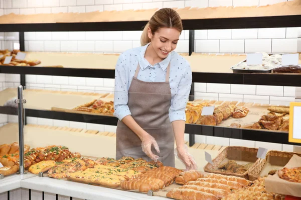 Beautiful woman near showcase with pastries in bakery shop