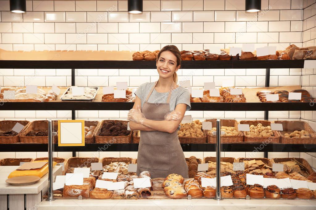 Beautiful woman near showcase with pastries in bakery shop