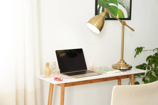 Lieu de travail élégant avec ordinateur portable moderne et produits cosmétiques sur la table près du mur de lumière. Blogueur beauté — Photo