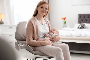 Evde koltukta oturan küçük bebeği ile anne