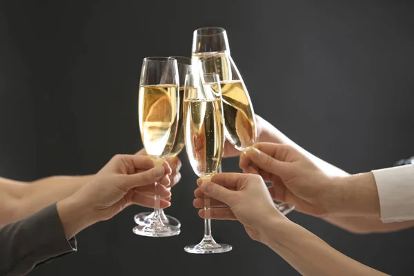 People clinking glasses of champagne on dark background, closeup — Stock Photo, Image