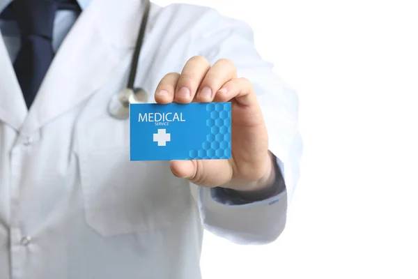 Lääkäri pitää käyntikorttia valkoisella, lähikuvassa. Terveyspalvelut — kuvapankkivalokuva