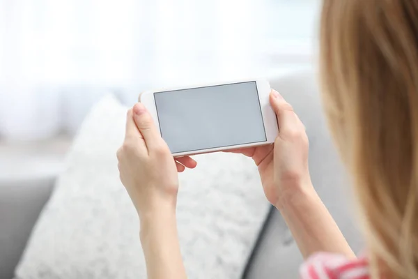 Giovane donna che utilizza la video chat su smartphone in soggiorno, primo piano. Spazio per il design — Foto Stock