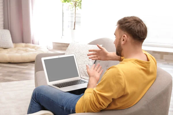 Hombre joven que utiliza el chat de vídeo en el ordenador portátil en la sala de estar. Espacio para el diseño — Foto de Stock