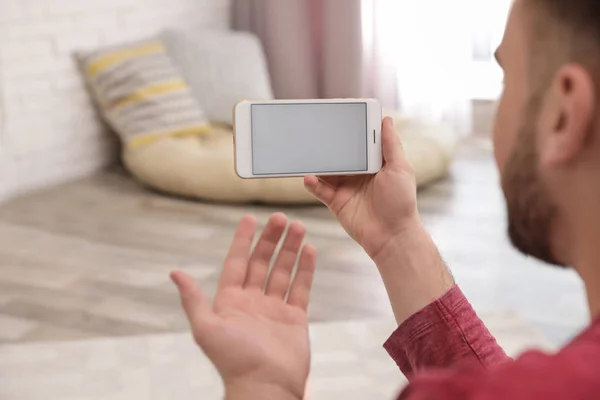 Молодой человек использует видео чат на смартфоне дома, крупным планом. Пространство для дизайна — стоковое фото