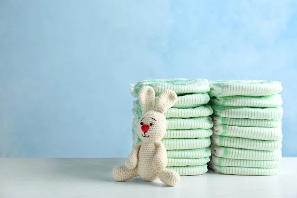 Renkli arka plan, metin için alan karşı masada bebek bezi ve oyuncak tavşan yığınları. Bebek aksesuarları — Stok fotoğraf