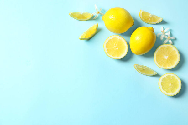 Frame made of lemons and flowers on color background, flat lay with space for text. Citrus fruits