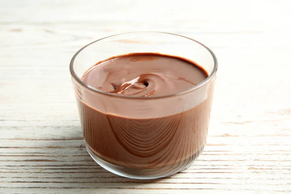 Vidro com creme de chocolate saboroso na mesa de madeira — Fotografia de Stock