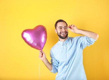 Renkli arka planda kalp şeklinde balon ile genç adamın portresi