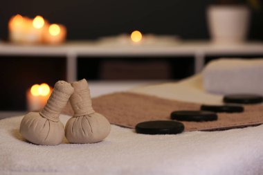 Spa salonunda masaj masasında bitkisel kompres ve taşlar. Metin için alan