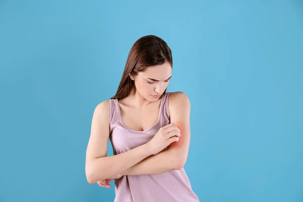 Mujer joven que se rasca la mano en el fondo de color. Síntomas alérgicos — Foto de Stock