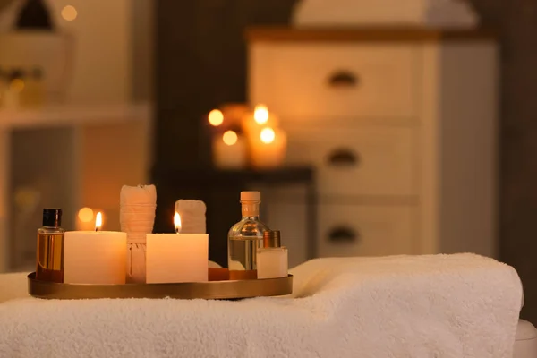 Kosmetik und brennende Kerzen auf Massagetisch im Wellness-Salon, Platz für Text — Stockfoto