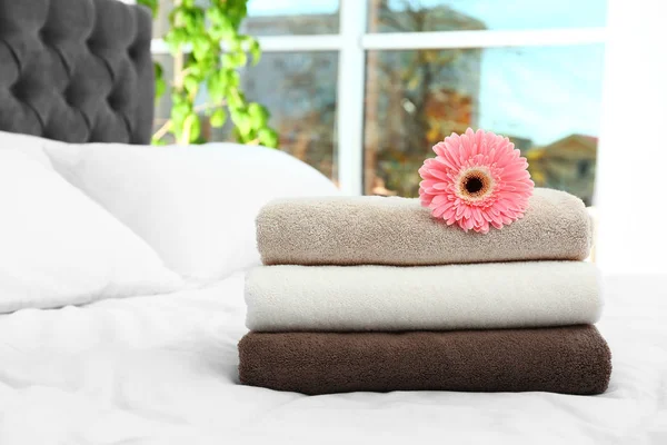 Stapel schone handdoeken en mooie Gerbera bloem op bed. Ruimte voor tekst — Stockfoto