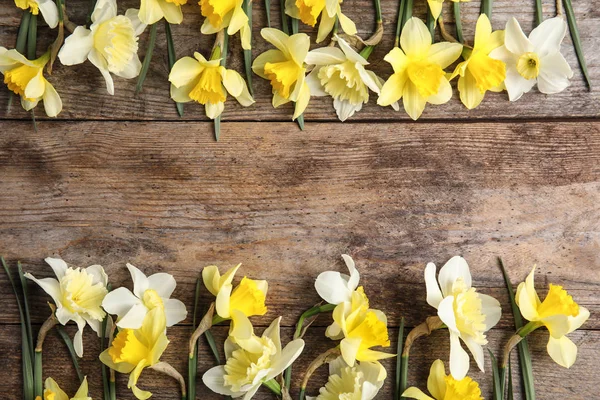 Composición plana con narcisos y espacio para texto sobre fondo de madera. Flores frescas de primavera — Foto de Stock