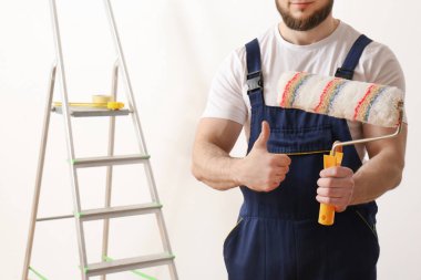 Boş odada boya silindiri ile erkek dekoratör, closeup. Metin alanı