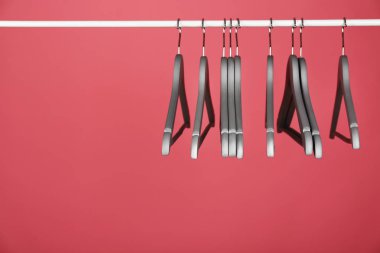 Renkli arka plana karşı metal rayüzerinde boş giysi askıları. Metin için alan