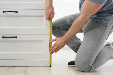 İç mekanlardaki çekmecelerin göğsünü ölçen adam, yakın çekim. İnşaat aleti