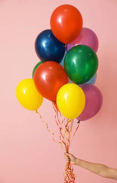 Mujer sosteniendo racimo de globos brillantes sobre fondo de color, primer plano. Tiempo de celebración — Foto de Stock